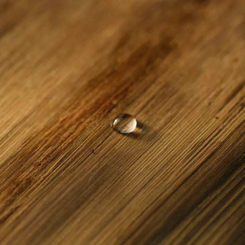 Gros plan sur le grain d’une planche de cèdre, une goutte d’eau posée dessus.